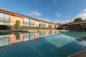 Een buitenzwembad, parasols bij het zwembad en ligstoelen