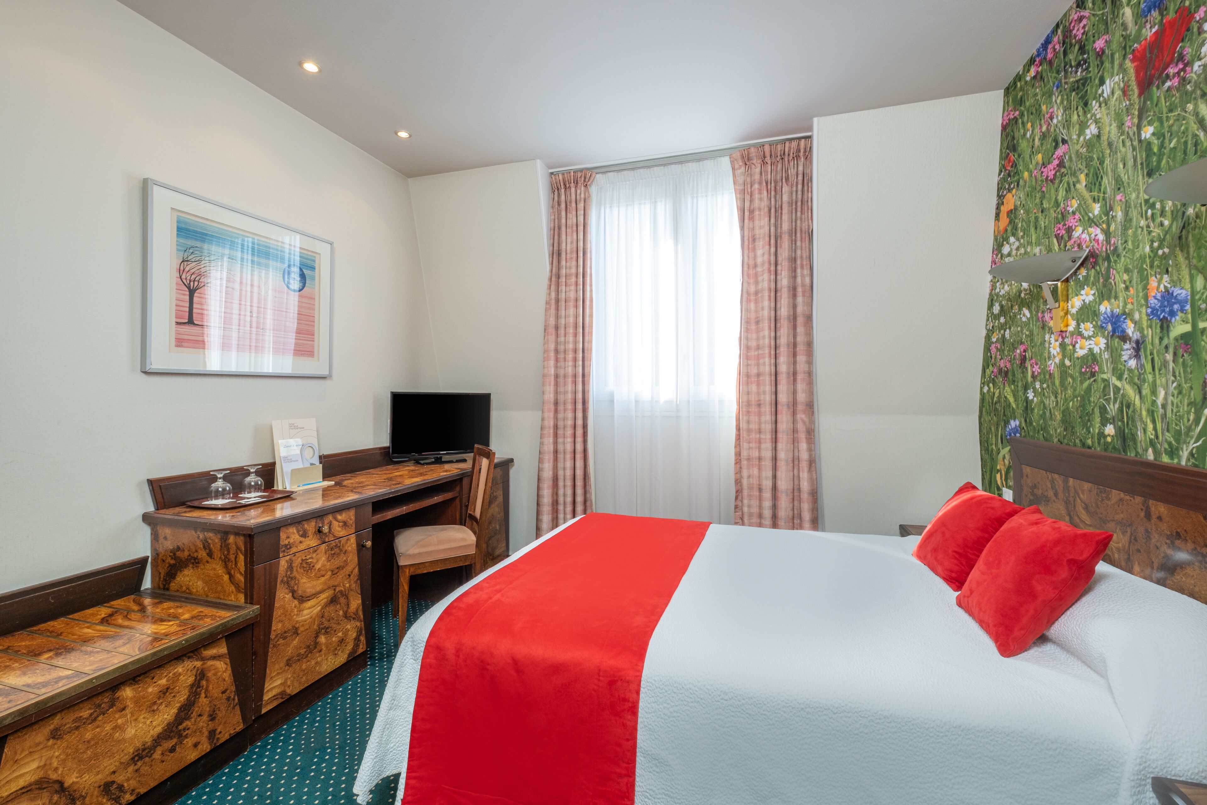Una habitación de hotel con cama, escritorio, silla, televisor y ventana con cortinas.