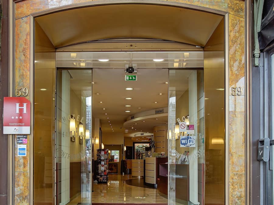 The entrance to Terminus Montparnasse with a red carpet, glass doors, and a sign indicating the hotel name.