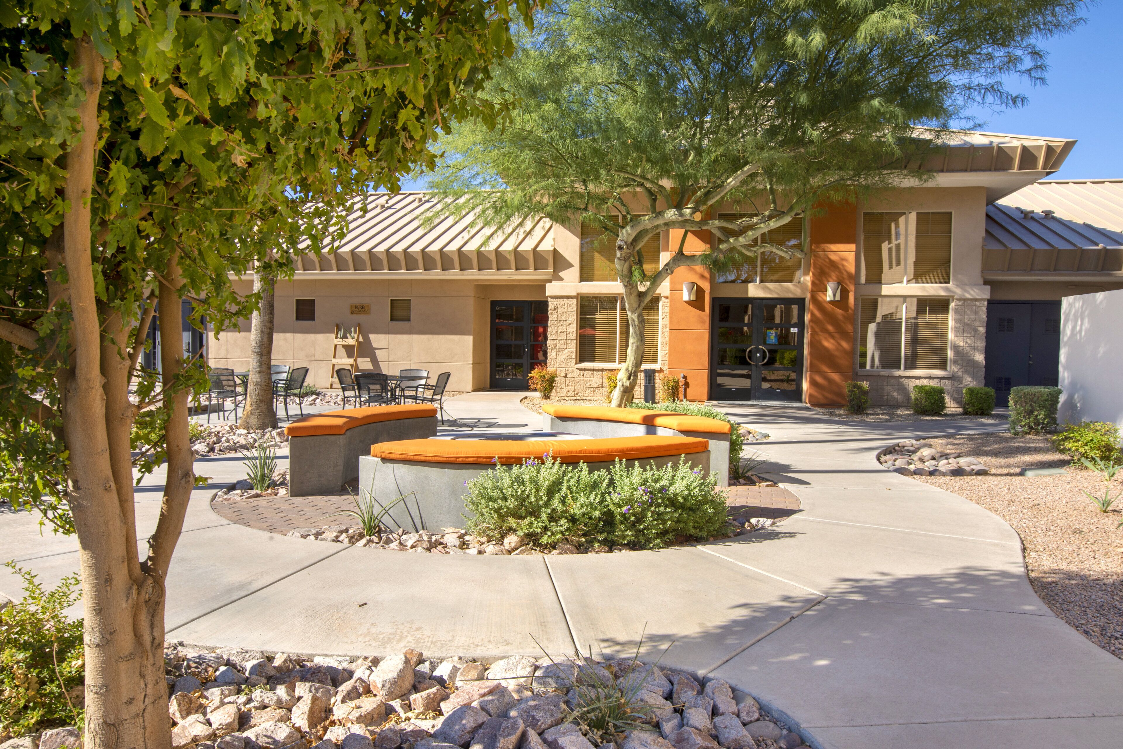 A building with a patio area, outdoor seating, and a stone pathway.