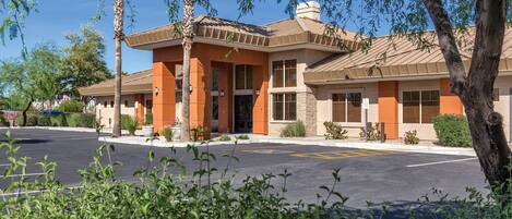 A building with a brown roof and orange walls, surrounded by greenery.