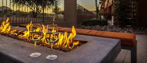A fire feature with two glasses of white wine.