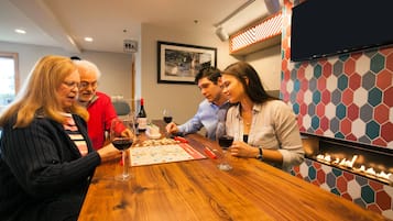 Un grupo de personas jugando un juego de mesa en una mesa de madera con copas y botellas de vino.
