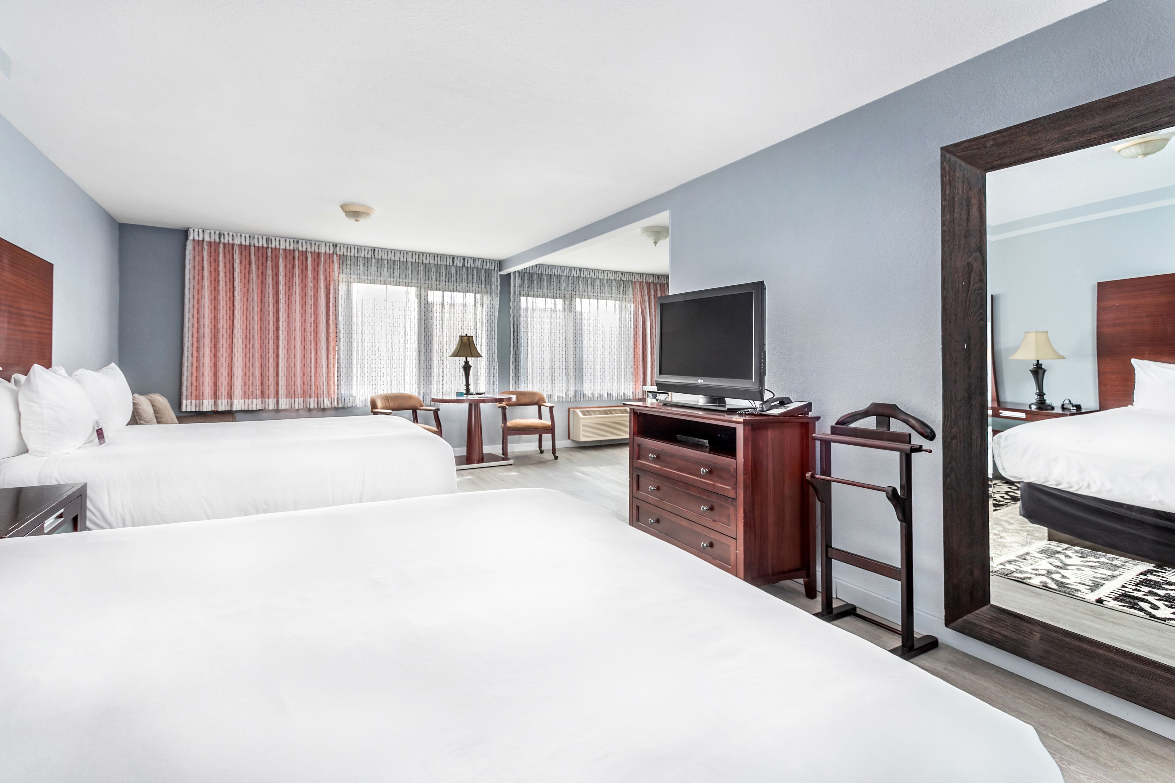 Quarto de hotel com duas camas, televisão, secretária e uma cadeira.