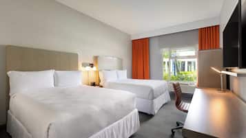 Ein Hotelzimmer mit zwei Betten, einem Schreibtisch, einem Stuhl und einem Fernseher.