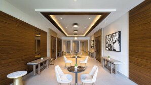 A modern hotel lobby with a central round table, white chairs, and a bench along the walls. - Four Points by Sheraton Caguas Real Hotel & Casino (Caguas)