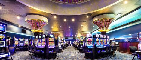 A casino with multiple gaming tables and slot machines, arranged in rows with a patterned carpet.