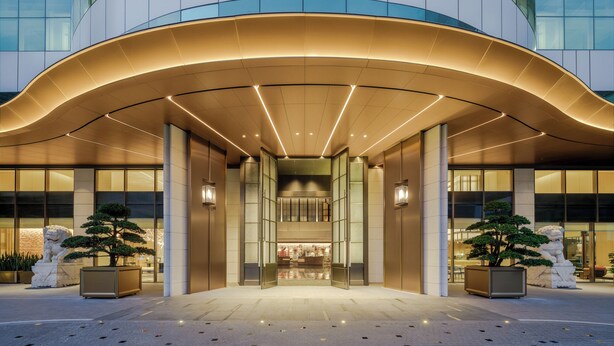 A modern hotel entrance with a curved canopy, large glass windows, and potted plants. - Canton Hotel Guangzhou, Tapestry Collection by Hilton (Guangzhou)