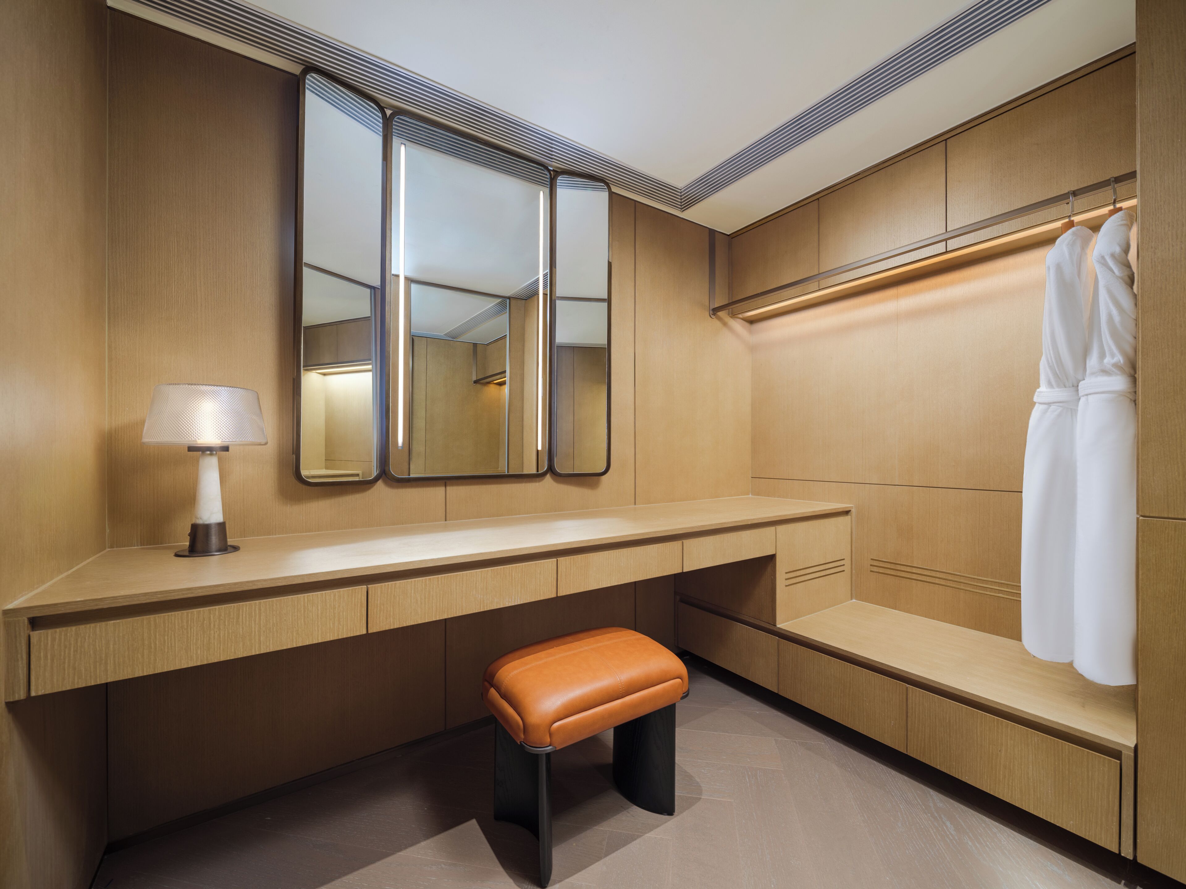 A modern bathroom with a wooden vanity, a bench, a mirror, and a towel rack.