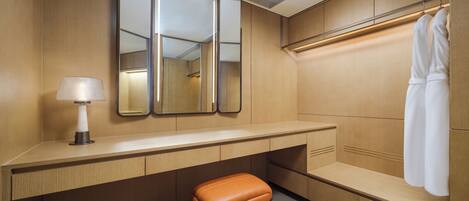 A modern bathroom with a wooden vanity, a bench, a mirror, and a towel rack.