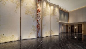 A spacious lobby with a polished marble floor, a large decorative tree with red flowers, and a modern elevator. - Canton Hotel Guangzhou, Tapestry Collection by Hilton (Guangzhou)