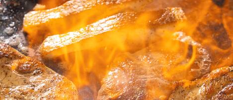 A close-up of grilled meat with visible flames.