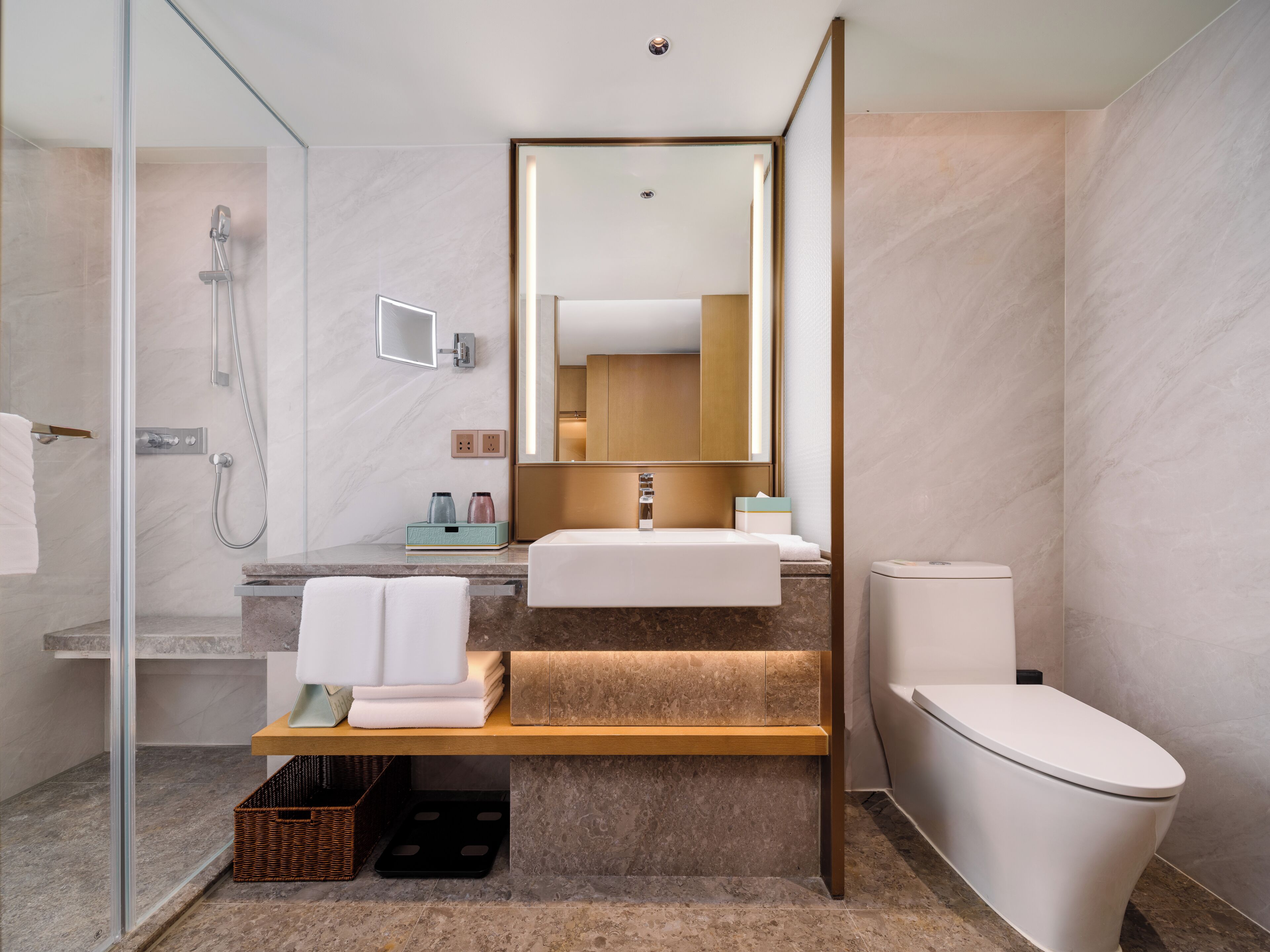 Un baño moderno con cabina de ducha de vidrio, lavabo, inodoro y espejo.