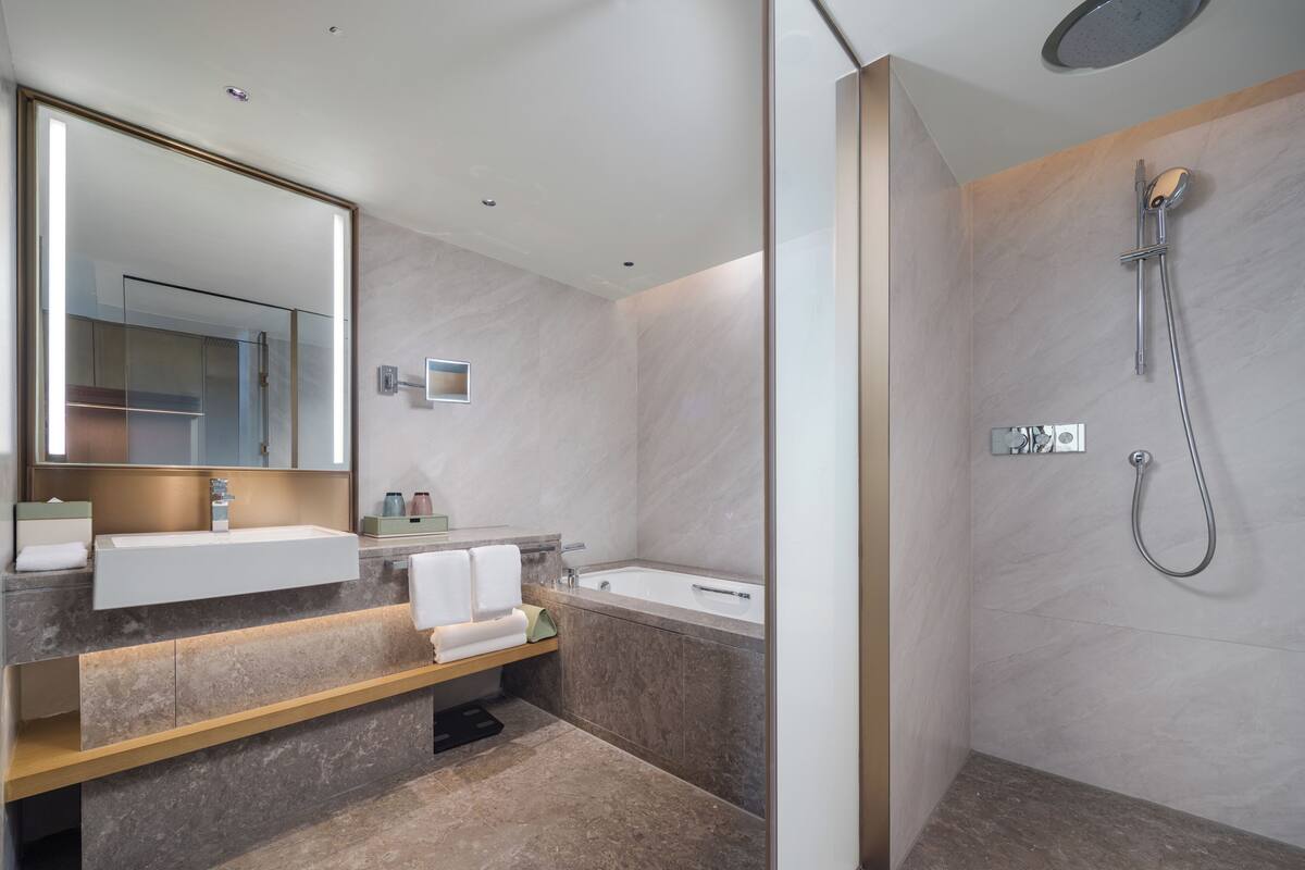 A modern bathroom with a large mirror, a sink, a bathtub, and a shower.