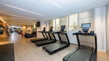 A gym with treadmills, exercise bikes, and a wall-mounted TV.