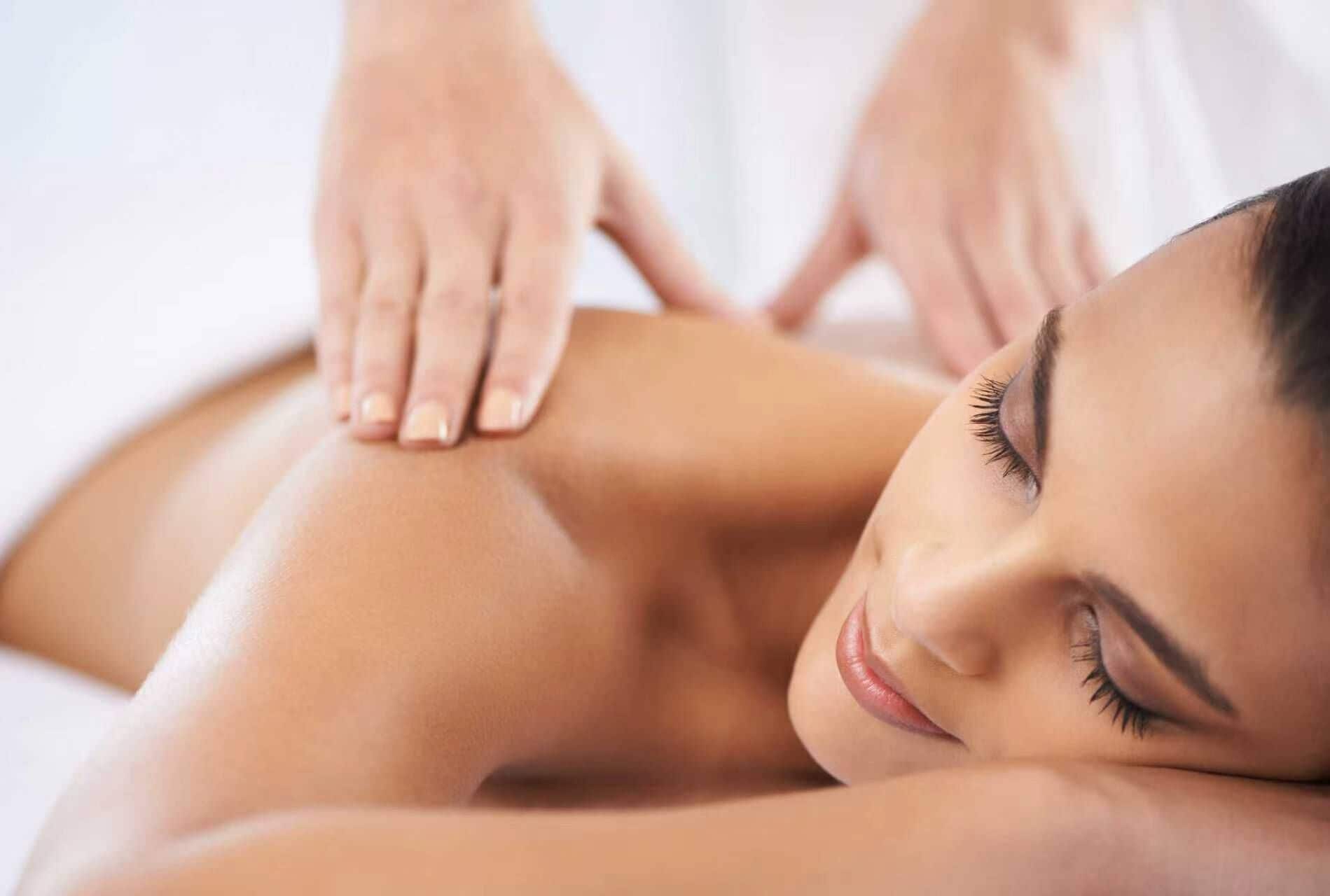 A person receiving a massage, with hands applying pressure to the back.