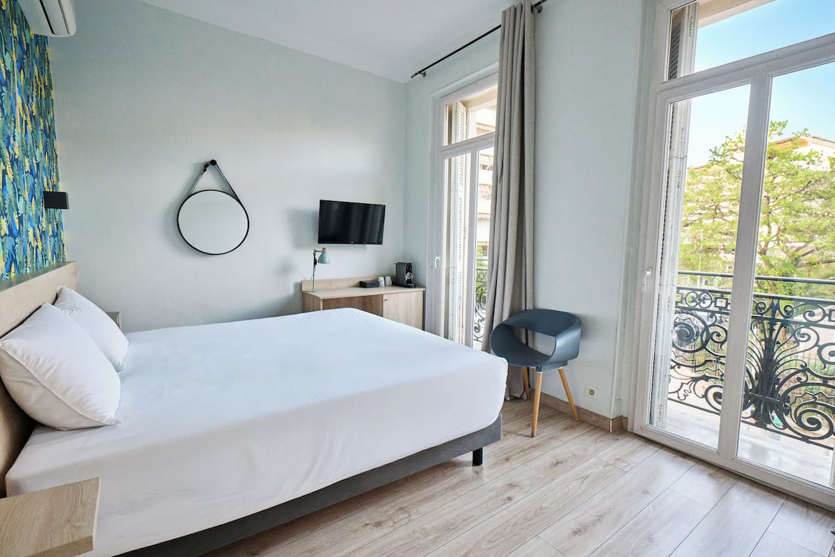 A bedroom with a bed, a TV, a desk, and a chair.