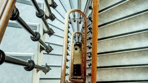 A spiral staircase with a wooden handrail and metal balusters. - Hotel Aria (Nice)