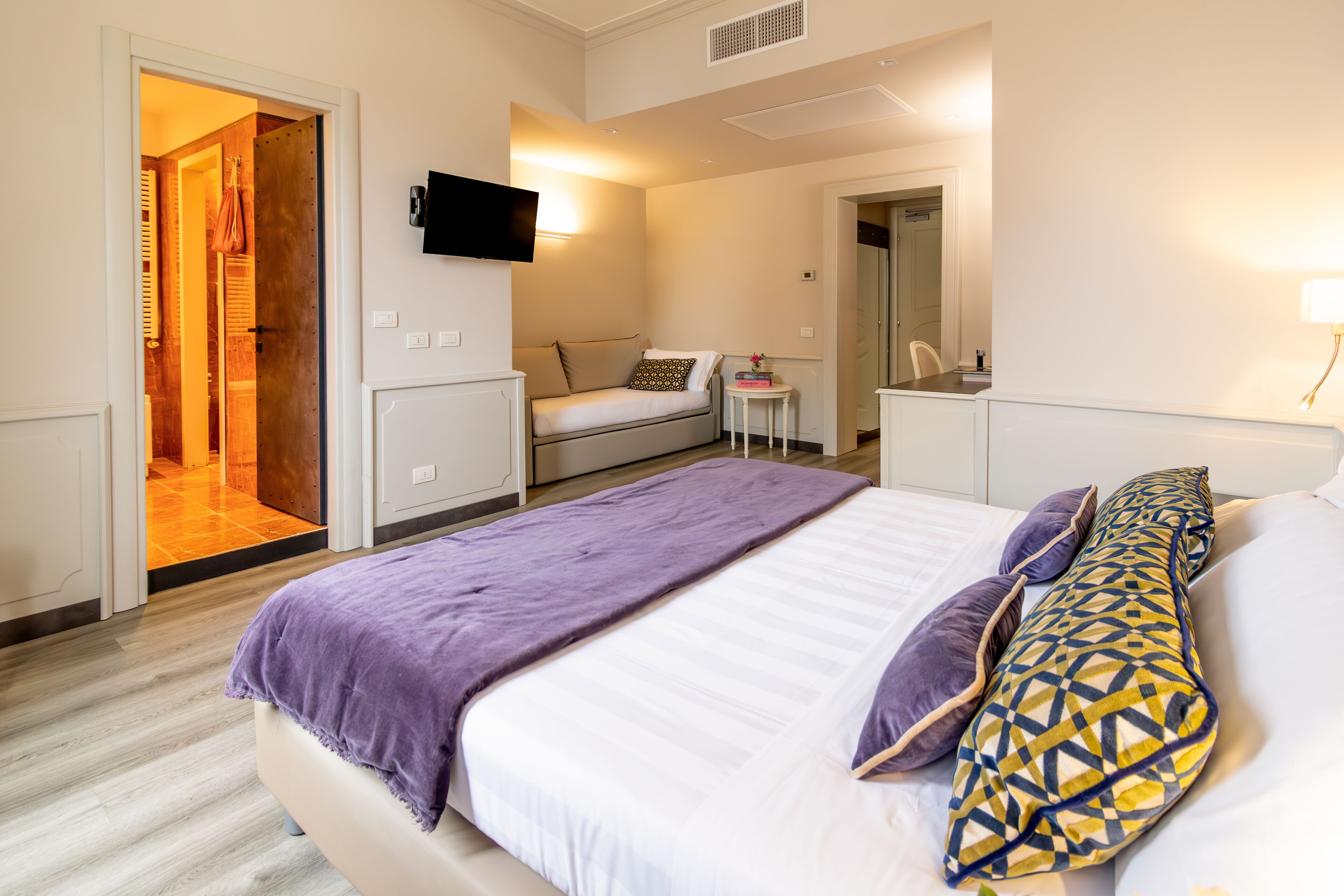 A bedroom with a bed, bedside table, and a TV mounted on the wall.