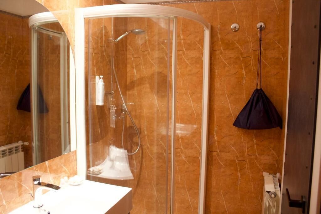 A bathroom with a glass-enclosed shower, a white sink, and a towel rack.