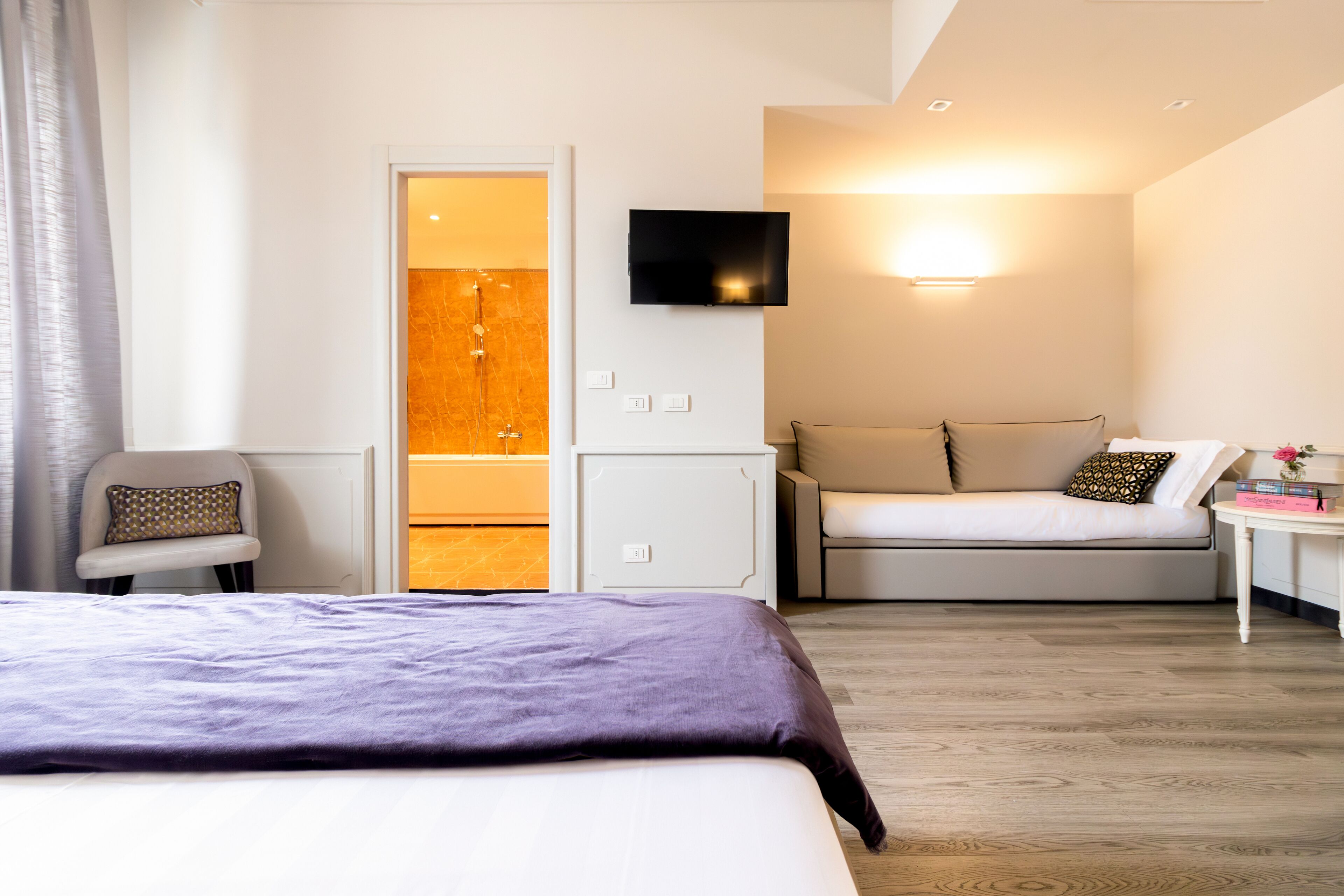 Une chambre d’hôtel moderne équipée d’un lit, d’un canapé, d’une télévision et d’une petite table.