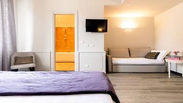 Une chambre d’hôtel moderne équipée d’un lit, d’un canapé, d’une télévision et d’une petite table.