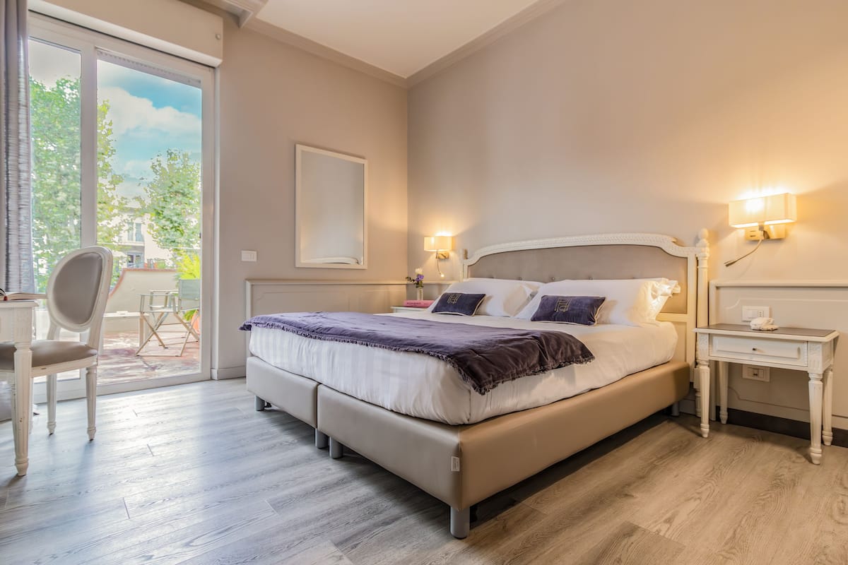 A bedroom with a bed, bedside tables, a chair, and a view of the outdoors.