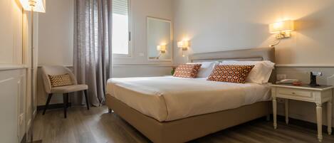 Una habitación de hotel con una cama grande, lámparas de noche, una silla y una mesita de noche.
