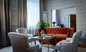 Una sala de estar con un sofá, dos sillones, una mesa de centro y un jarrón con flores.