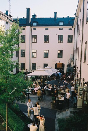 A courtyard with outdoor seating, surrounded by buildings with multiple windows and a staircase leading to an upper level. - NOFO Hotel, WorldHotels Crafted (Stockholm)