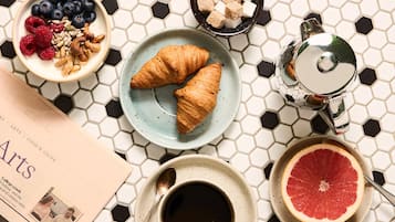 Desayuno con croissants, pomelo, café y un periódico.