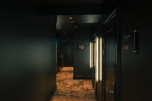 A hallway with a sign indicating a subway station, a door labeled 'Queens,' and a patterned floor. - NOFO Hotel, WorldHotels Crafted (Stockholm)