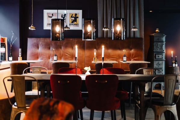 Interior de restaurante con cabinas de cuero, lámparas colgantes y una estufa antigua.