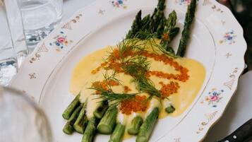 A plate of food with asparagus and a creamy sauce, accompanied by a knife and a glass.