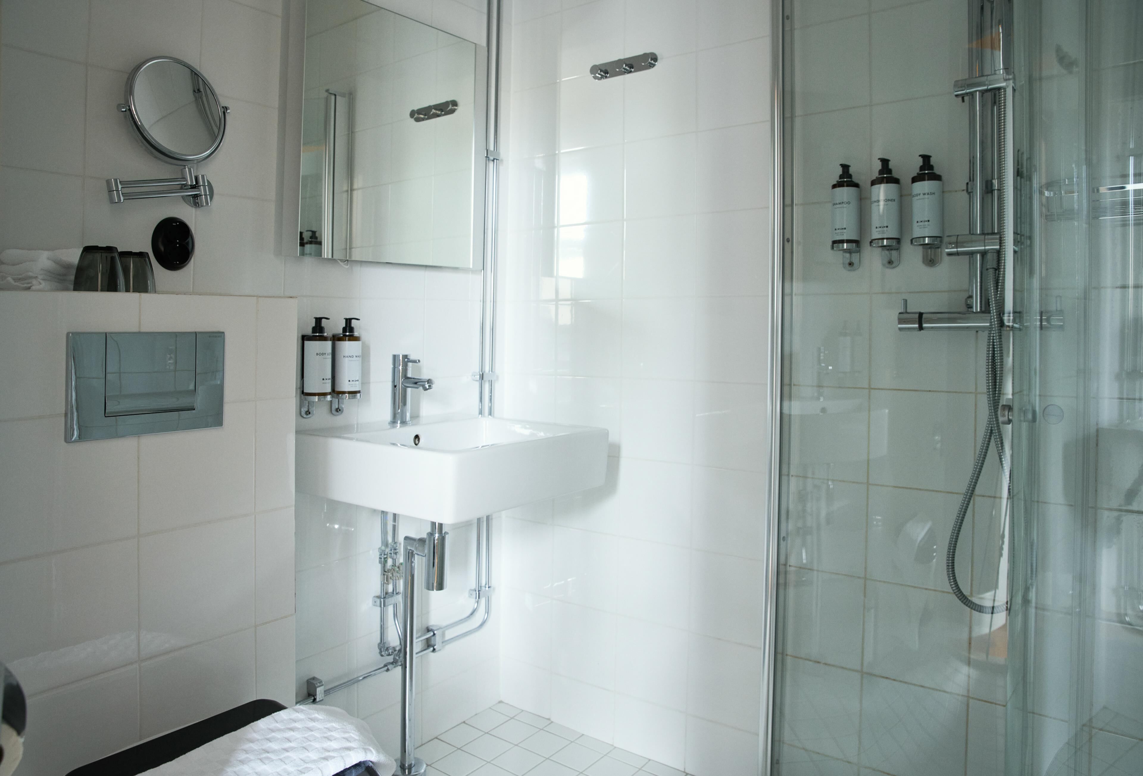 Une salle de bain moderne avec une douche à parois de verre, un lavabo blanc et des articles de toilette.