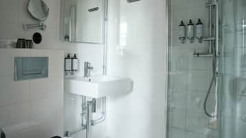 Ein modernes Badezimmer mit einer Duschkabine, einem weißen Waschbecken und Pflegeprodukten.