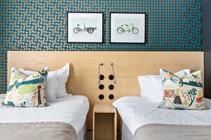 Habitación de hotel con dos camas, cabecera de madera y pared con diseño circular.