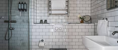 A modern bathroom with a glass shower enclosure, a white sink, a toilet, and a towel rack.