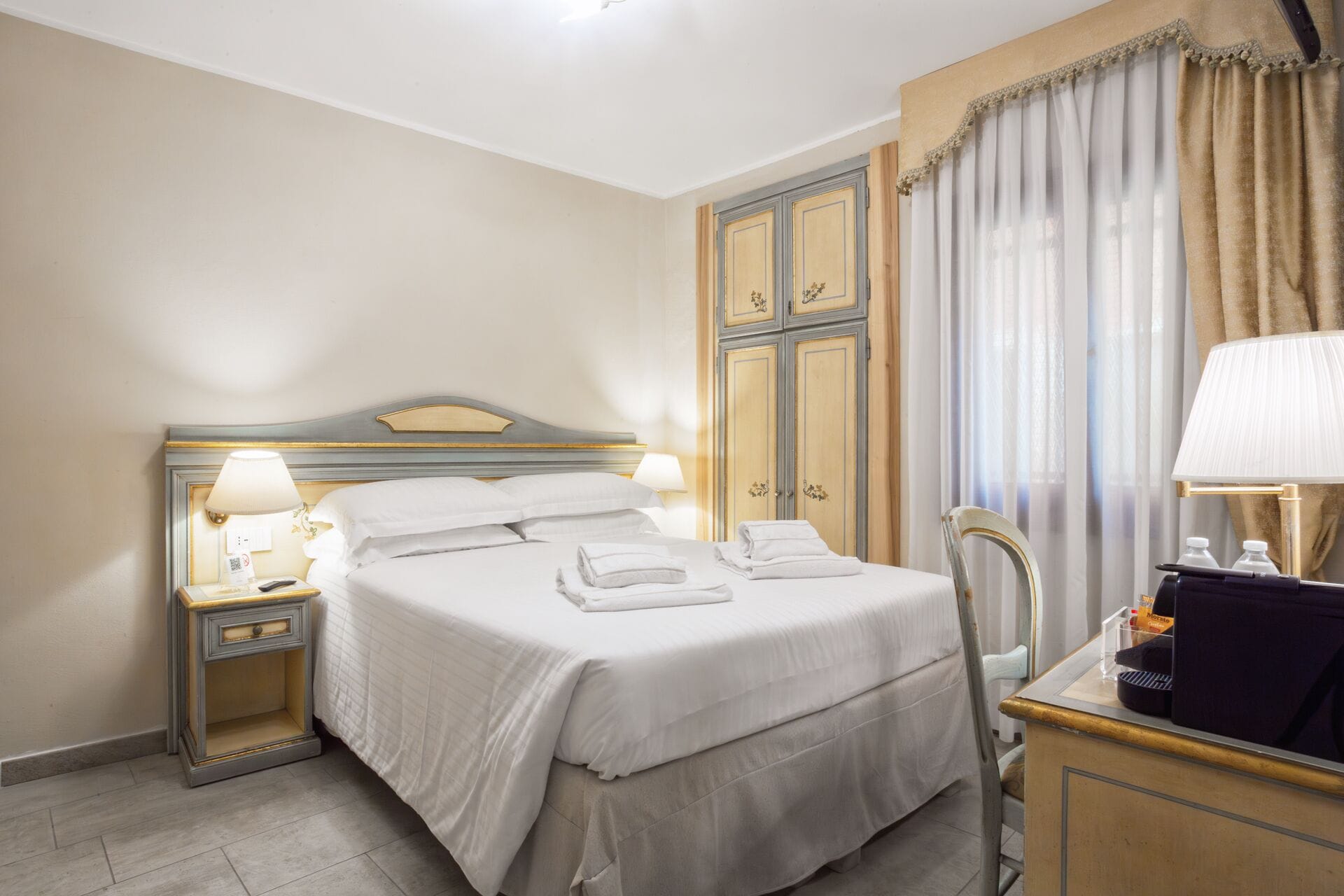 Une chambre d’hôtel comprenant un lit, des tables de chevet, un bureau avec une lampe et une chaise.