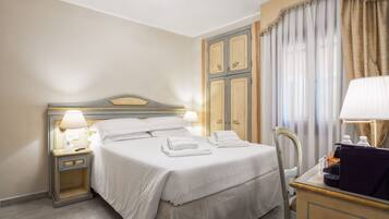 Une chambre d’hôtel comprenant un lit, des tables de chevet, un bureau avec une lampe et une chaise.