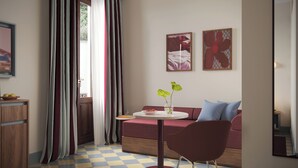 A modern room with a checkered floor, a round table with a vase, a sofa, and two framed artworks on the wall. - Numa Florence della Robbia (Florence)