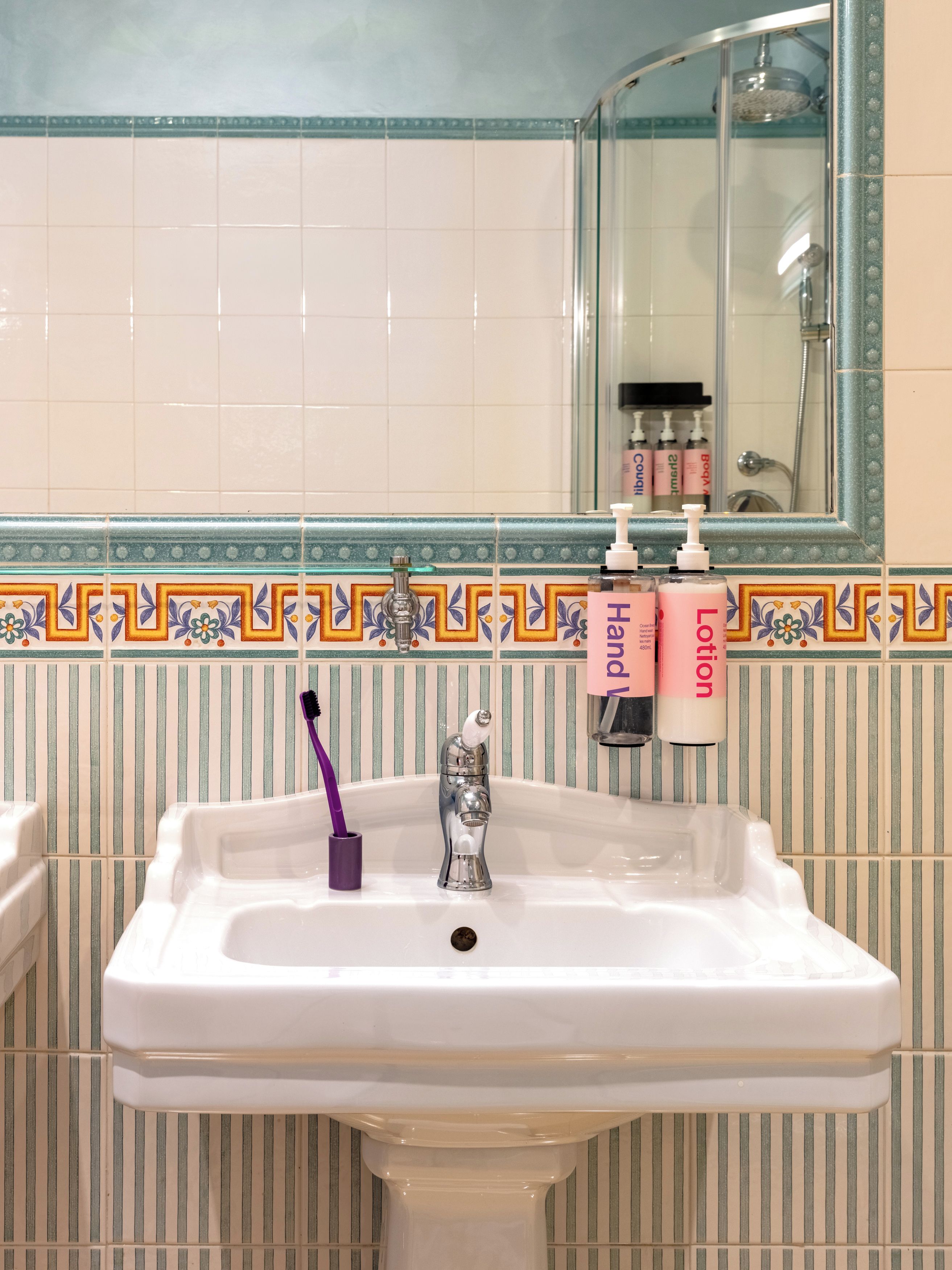 A bathroom sink with a toothbrush holder, a mirror, and toiletries.