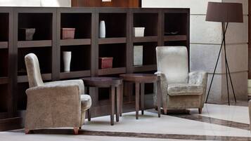 Una habitación con dos sillones, una mesita y una estantería con varios objetos decorativos.