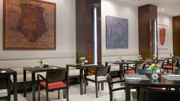 A modern restaurant with wooden tables and chairs, large abstract paintings on the walls, and a clean, minimalist design.