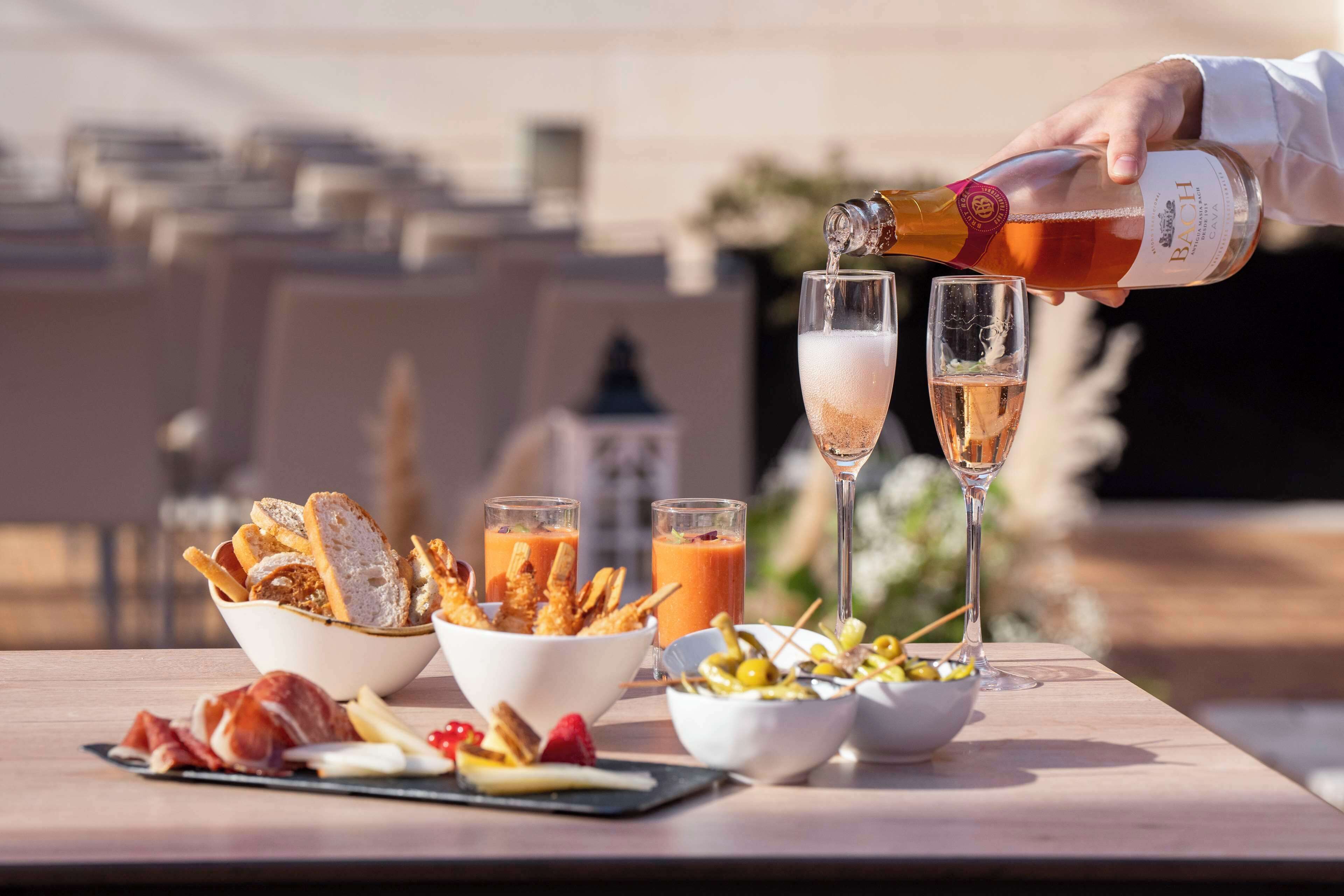 Una mesa con diversos alimentos y bebidas, incluyendo una botella vertiéndose en un vaso.