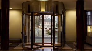 Una puerta giratoria con vista a un edificio de arcos y un árbol al fondo.