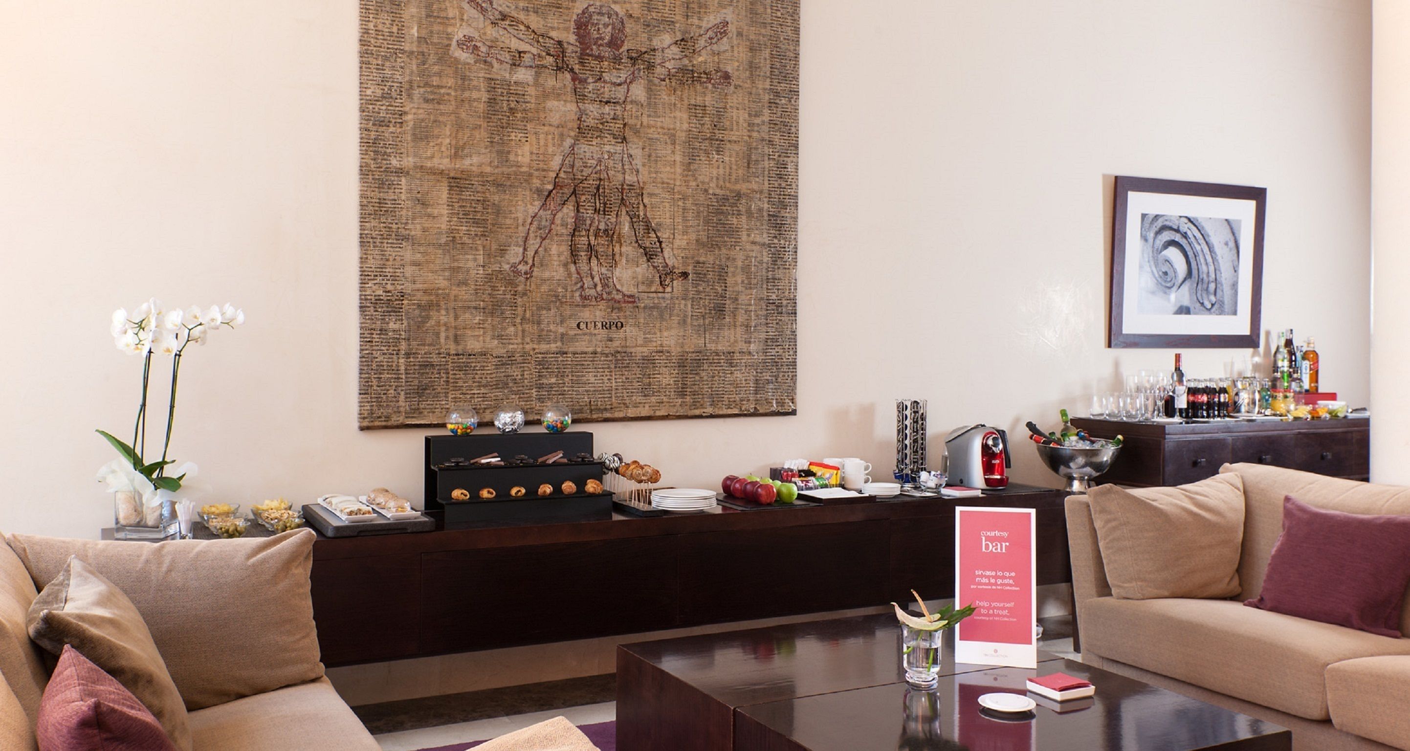 A hotel lobby with a reception desk, a coffee bar, and a seating area with sofas.
