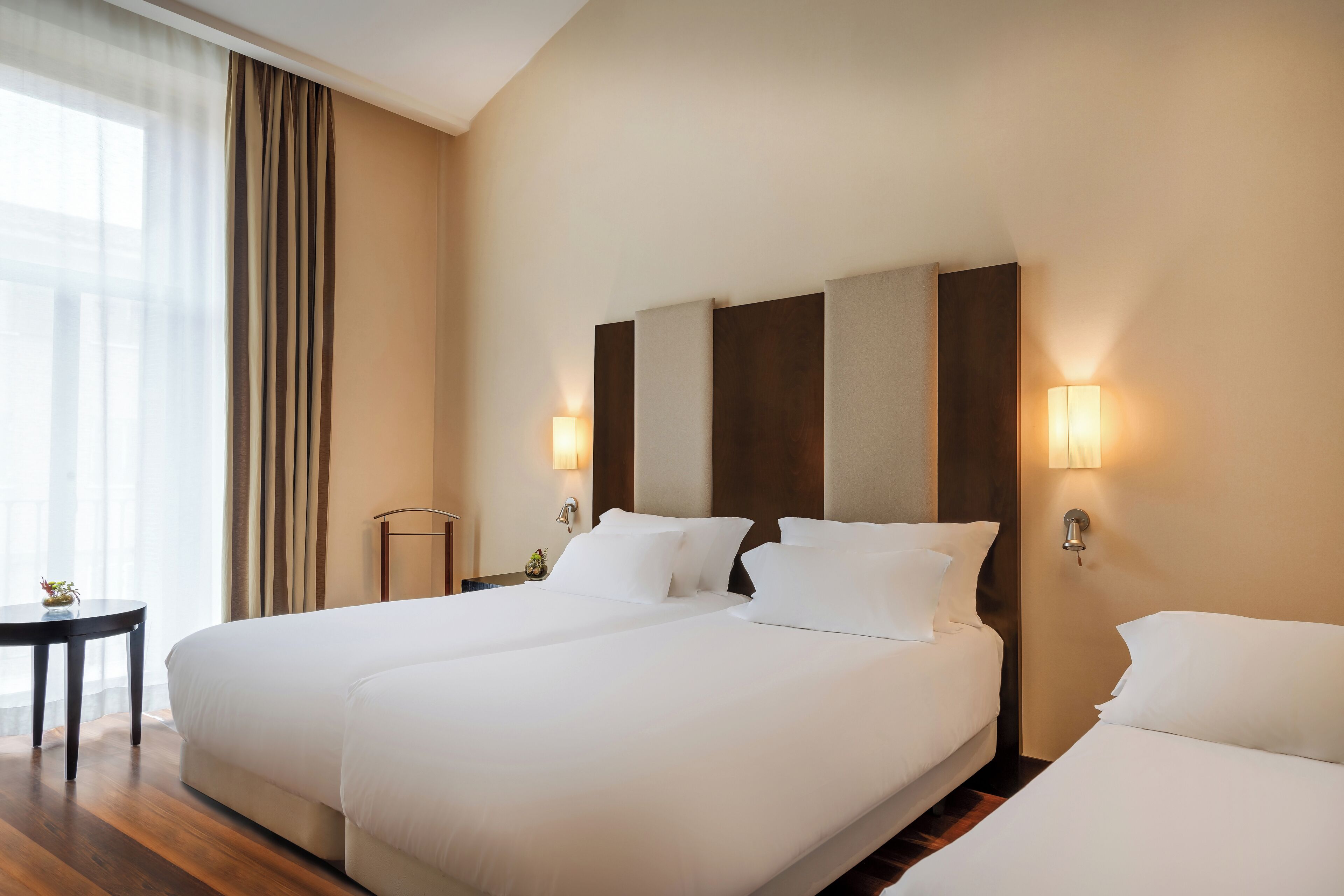 Una habitación de hotel con dos camas, una mesita y una lámpara.