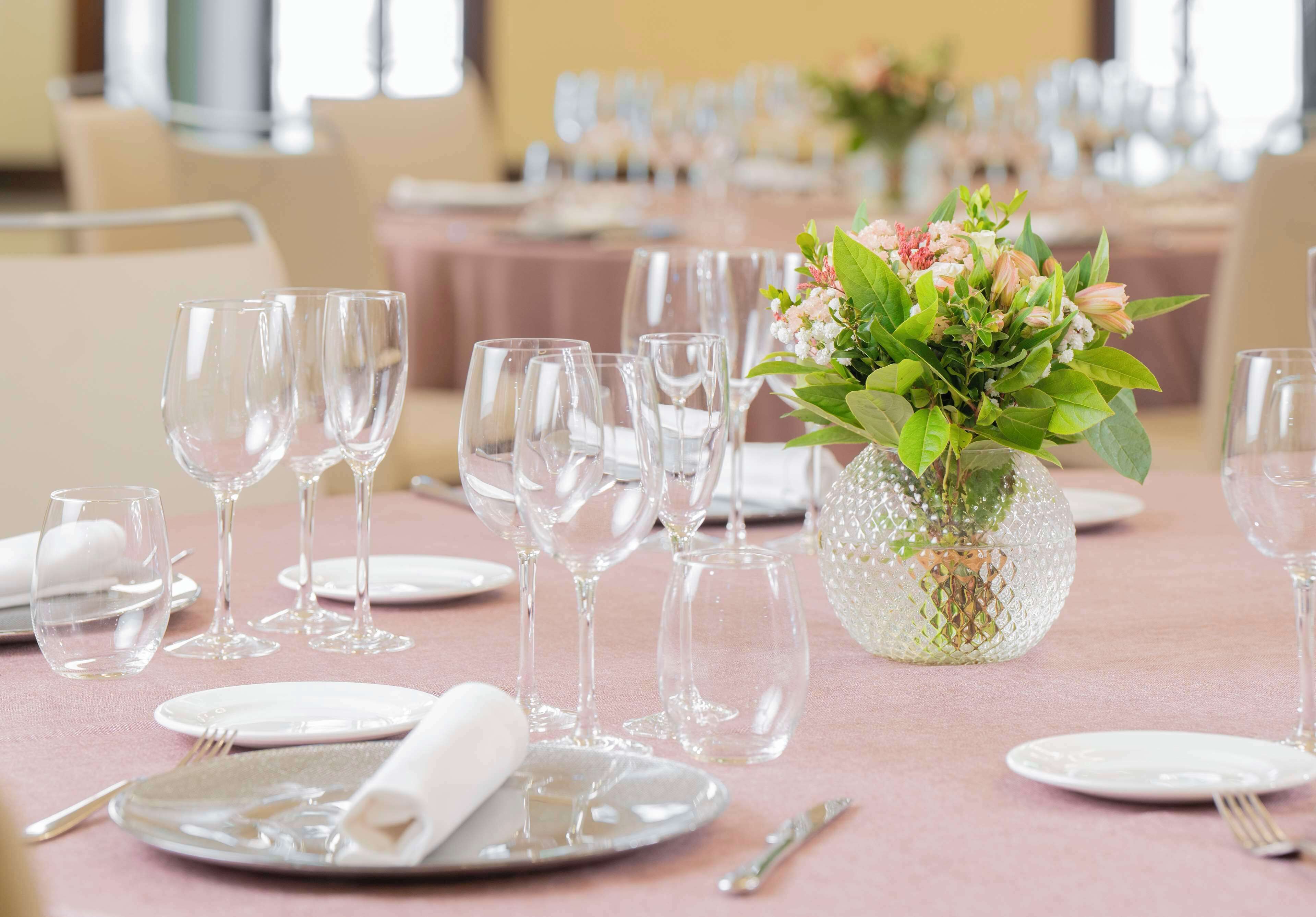 A table set for a formal event with clear glassware, folded white napkins, and a decorative vase with flowers.