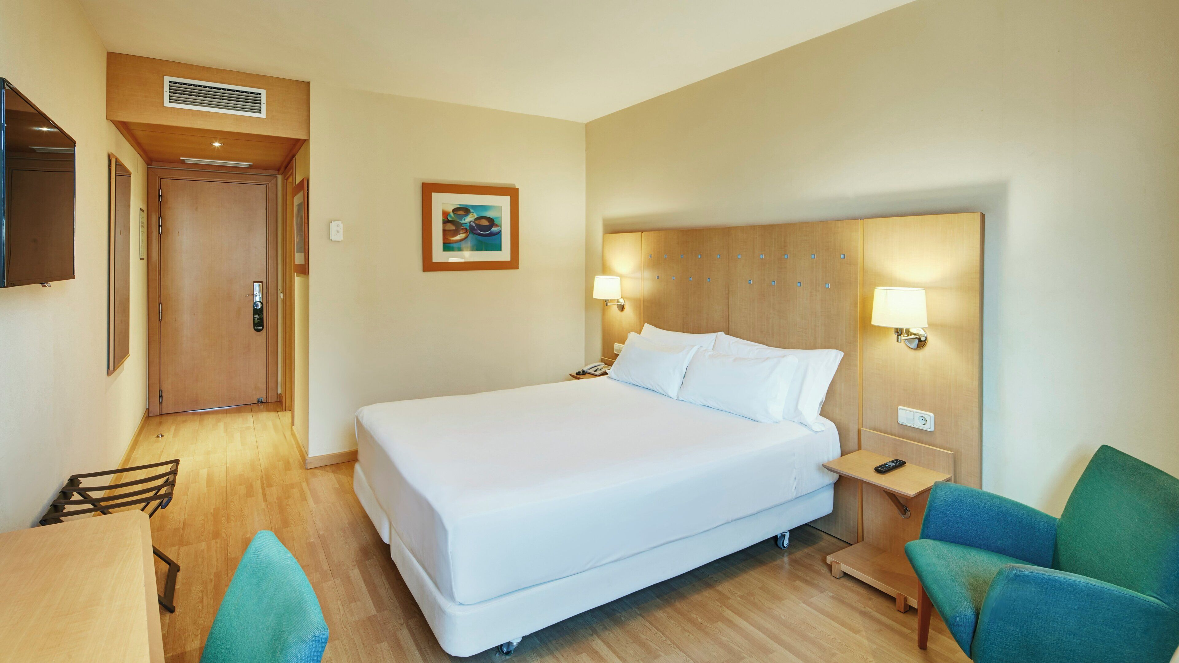 A hotel room with a large bed, bedside tables, a desk, and a chair.